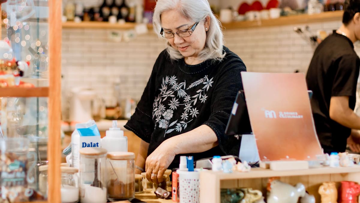 Seorang wanita berdiri di belakang kaunter sebuah kedai kecil.
