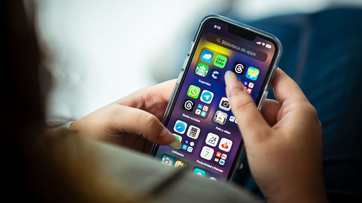Seorang wanita memegang telefon pintar yang memaparkan senarai aplikasi.